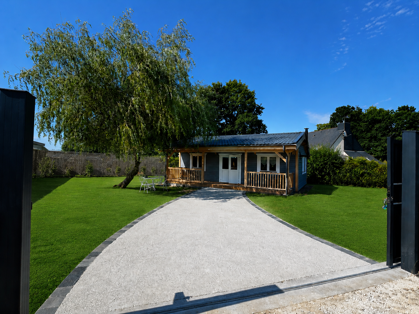 Chalet nordique en bois sous un ciel breton, entouré d'un saule pleureur